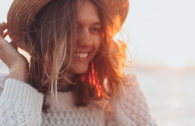 woman with hand on hat outside