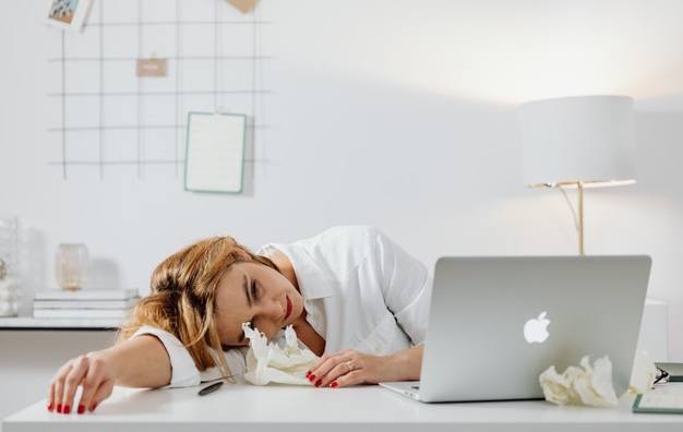 woman lying on table next to laptop in office