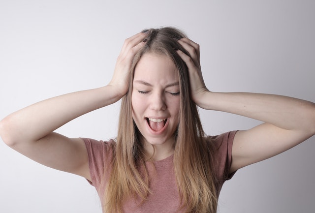 woman stressed mouth open with hands on her head 