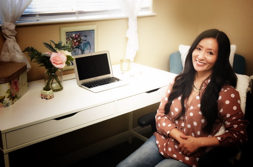 Lorin's profile picture looking up sitting at office desk in pink and white polka dot shirt